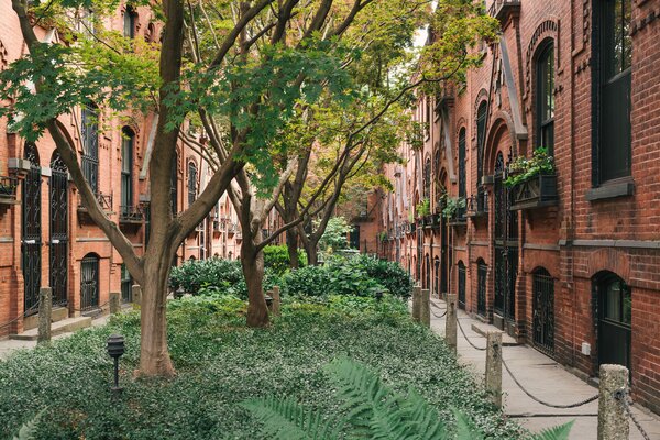 The home is one of 34 identical workers’ cottages lining a lush central courtyard. Cloistered from street traffic by iron gates at either end, the row houses feature paired arched doorways under Gothic gables, decorative brickwork, and delicate wrought iron over windows and doors.  