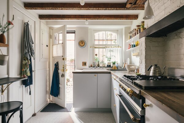 During the restoration process, the couple uncovered the original wooden beams and brick hearth. To emphasize the European cottage style, they installed a French range and kept cabinets and shelves at an almost rustic simplicity.  