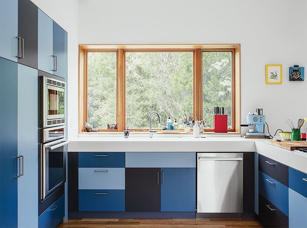 Be bold with colors, and turn your kitchen into a work of art with cabinet doors of different shades of color. In this East Tennessee home, laminate kitchen cabinets in three shades of blue and Glacier White Corian top completes a fun and modern composition.