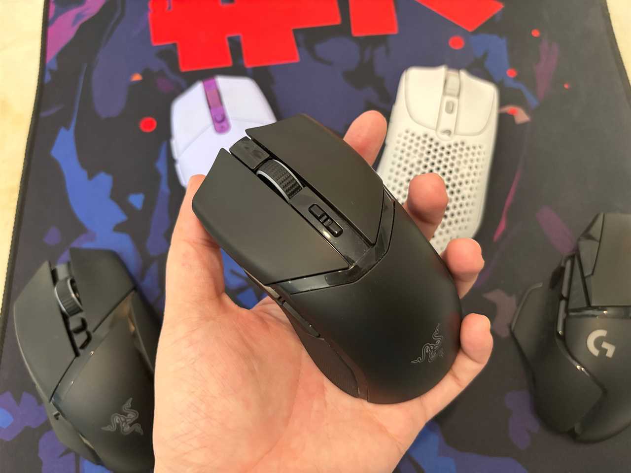 the razer cobra pro held in a hand in front of other wireless gaming mice