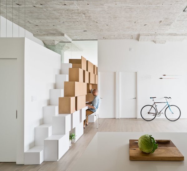 In the family room, cabinets open up to create an office desk. The steps on the left lead up to a mezzanine space that serves as play space for the children and a sleeping area for guests.