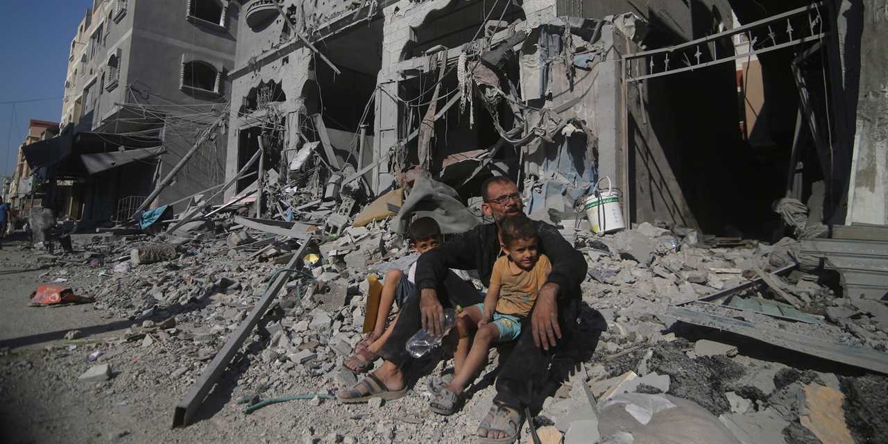 Palestinians sit outside their house following Israeli airstrikes in Rafah refugee camp