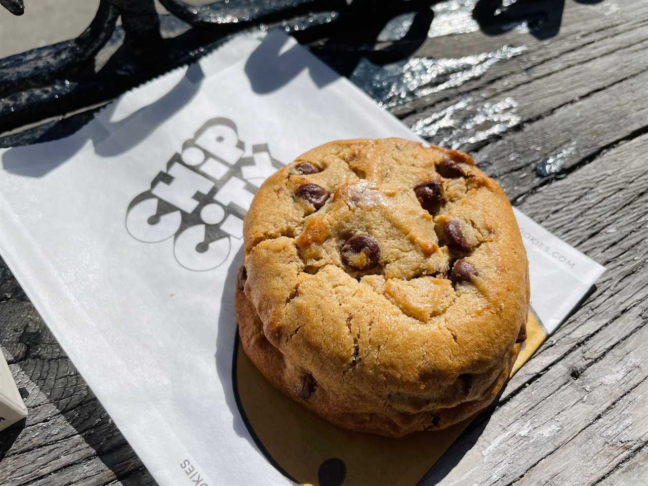 a chocolate chip cookie from Chip City sits on a table underneath a paper bag