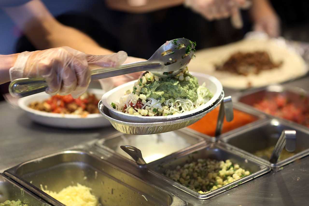 Someone dolloping guacamole on a Chipotle bowl.