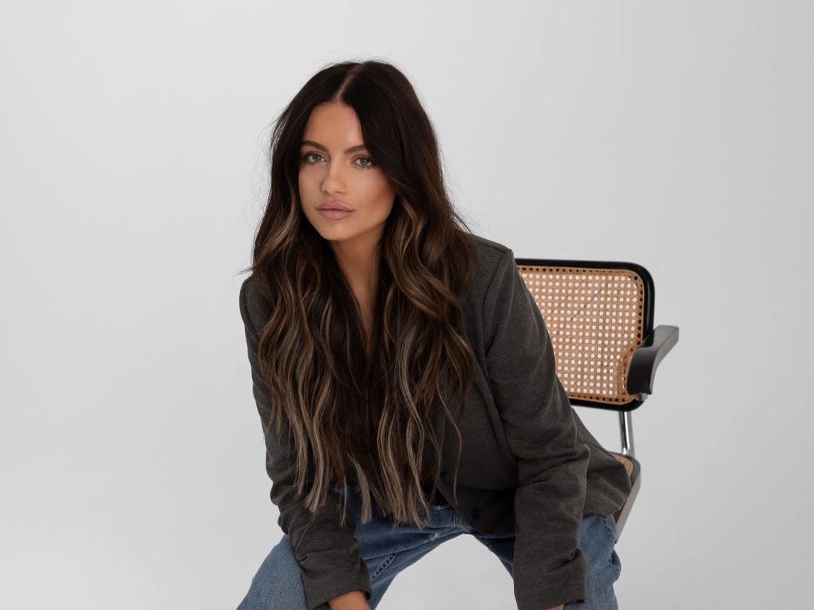 a woman sitting in a chair in a white room