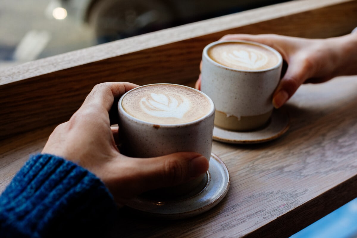 Close up woman and man holding cups of coffee on table