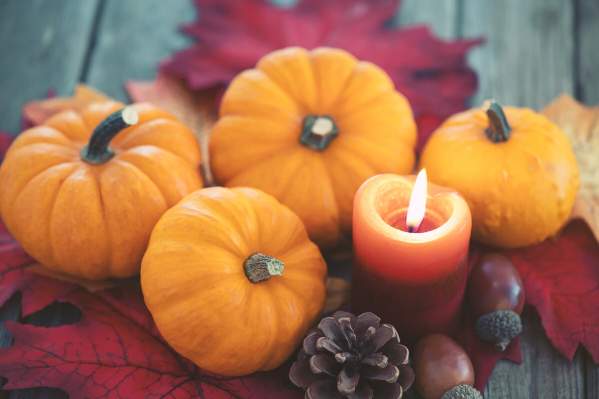 Thanksgiving decoration with pumpkins and candles on illuminated background and a rustic wooden table