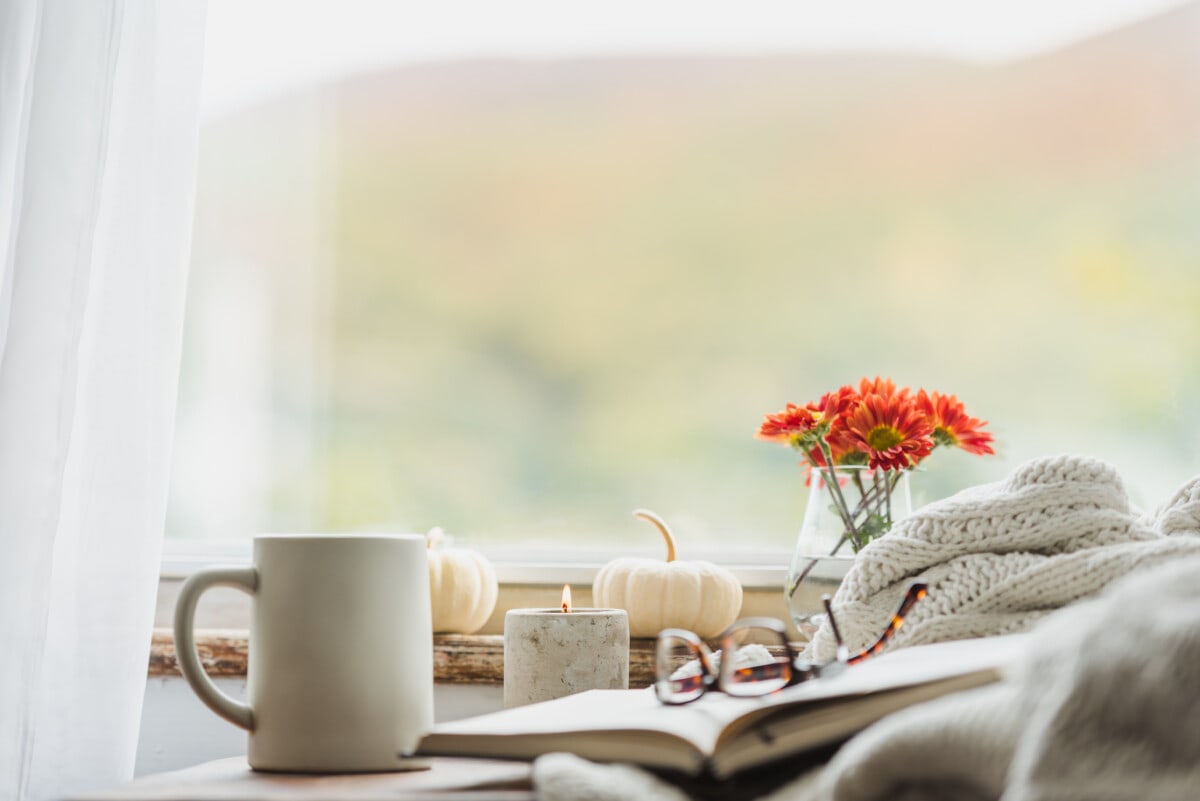 A nice warm looking reading nook in the fall that conveys the idea of being comfortable at home in autumn with a cup of coffee or tea and reading a good book.