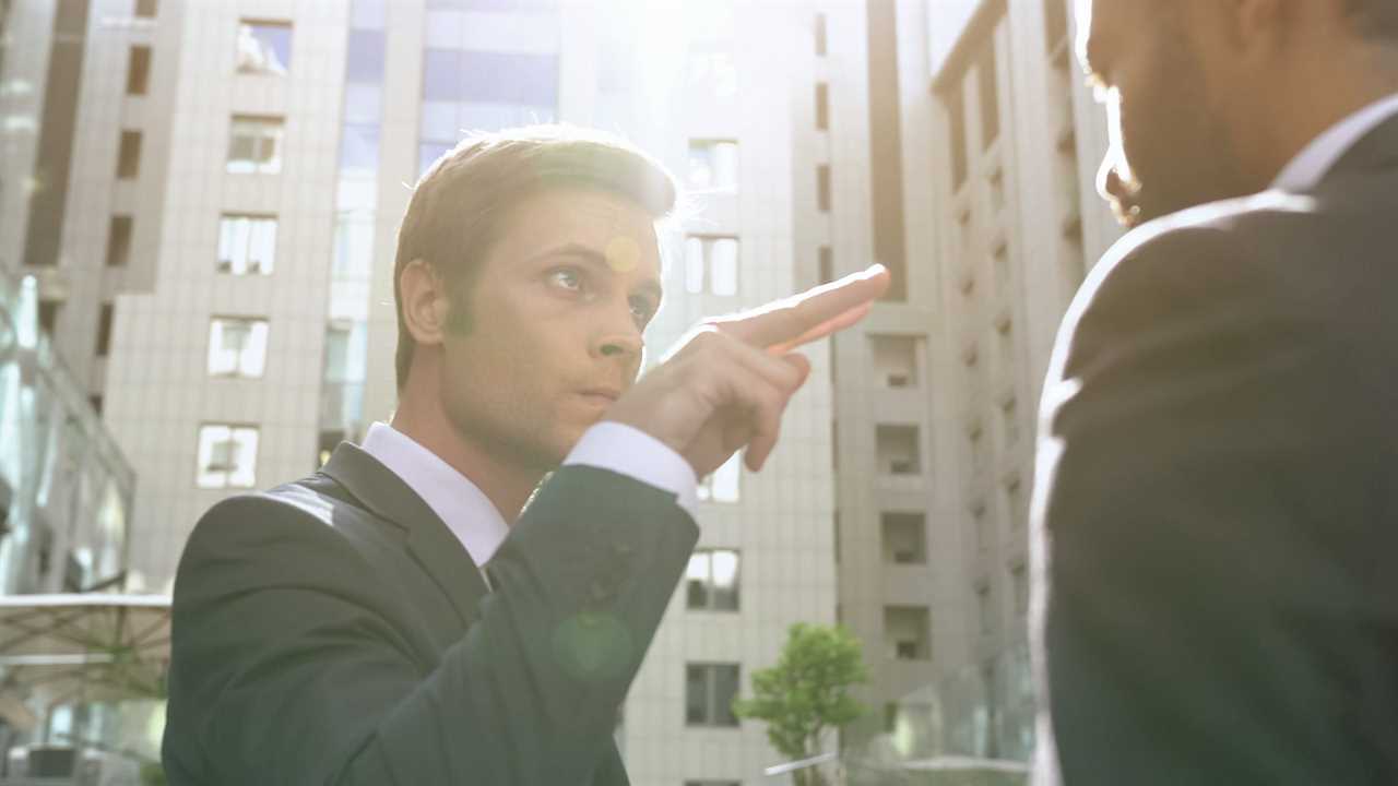 A man in business attire aggressively points at another man off screen.