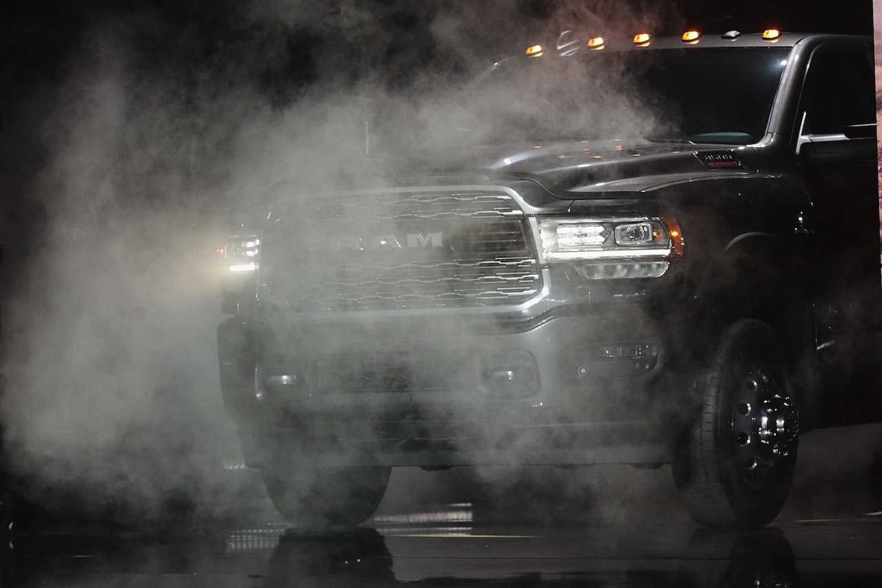 A Dodge Ram 3500 truck on a stage behind fog with its headlights illuminated