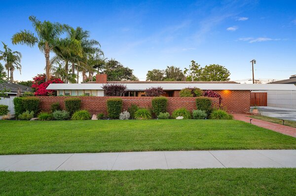 A long brick wall partially covers the front facade, enhancing the home's sense of privacy.