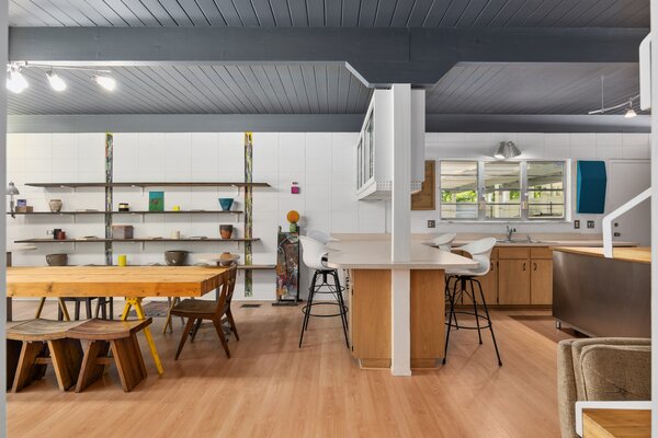 Inside, a L-shaped countertop offering bar-stool seating delineates the open kitchen from the main dining area. The gray-painted ceiling pops against the surrounding neutral palette.