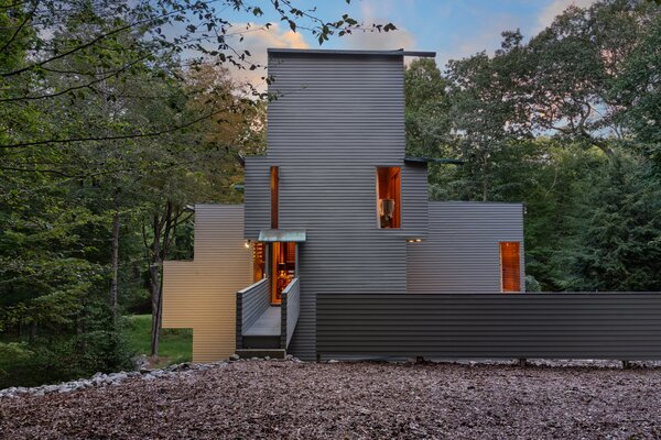 Upon arrival, a long, wooden walkway leads to the multi-story, geometric home, which sits surrounded by a thick forest and features soothing sounds of the nearby Saugatuck River.