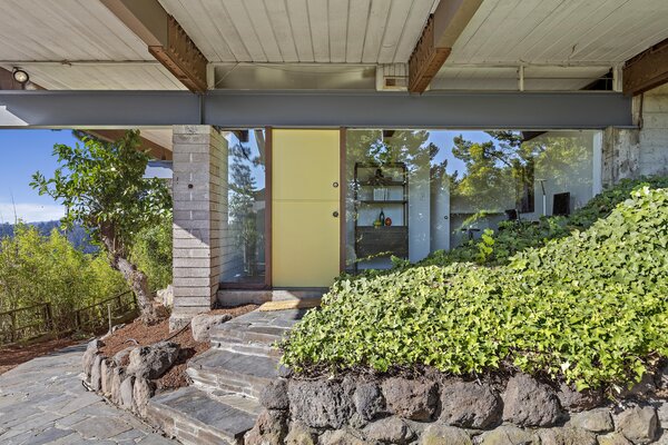 A bright yellow door set under the steel framing pops against the brick, stone, and glass.