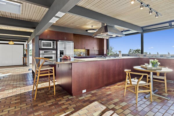 Expansive glazing spans the open kitchen, inviting warm sunshine inside while also framing striking views of the San Francisco Bay and surrounding greenery.