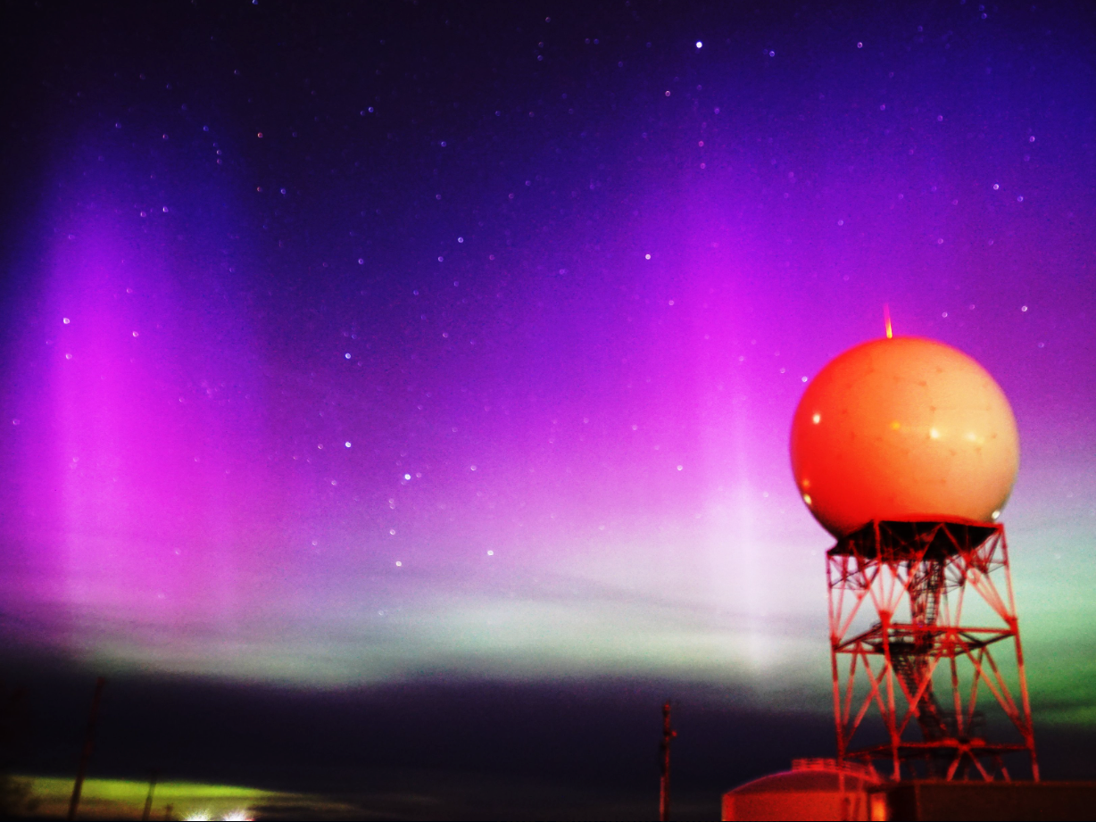 A picture from Riverton's national weather service in Wyoming shows purple and green northern lights shining behind a spherical structure in the foreground.