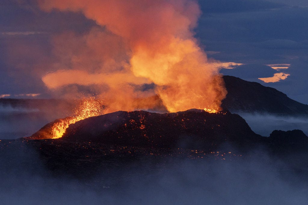 An image shows a volcano erupting above the clouds, a cloud of steam rises above the volcano.