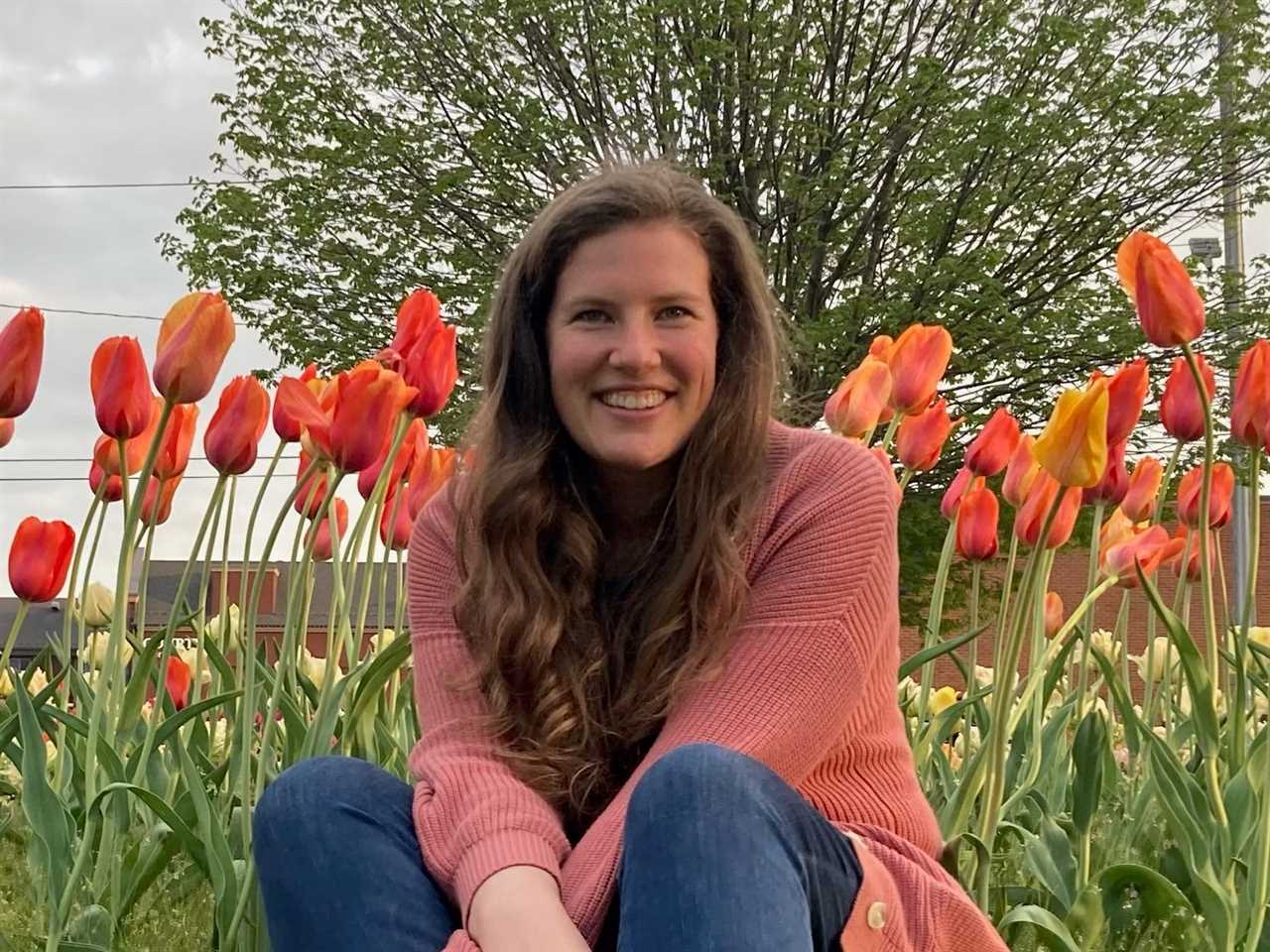 a woman sitting in front of tulips