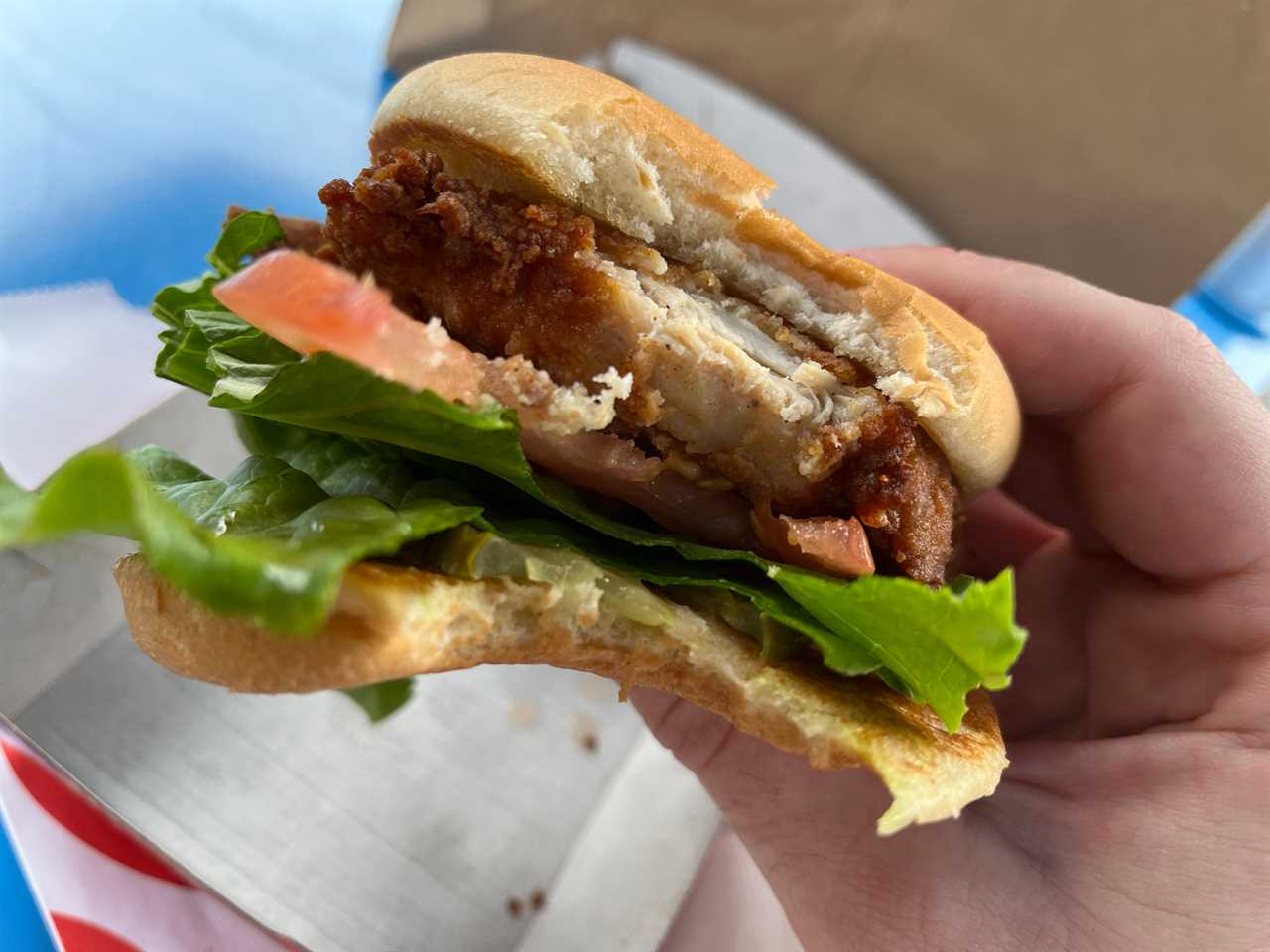 A Chick-fil-A chicken sandwich with a bite taken out of it, held by the reporter at a Little Blue Menu location