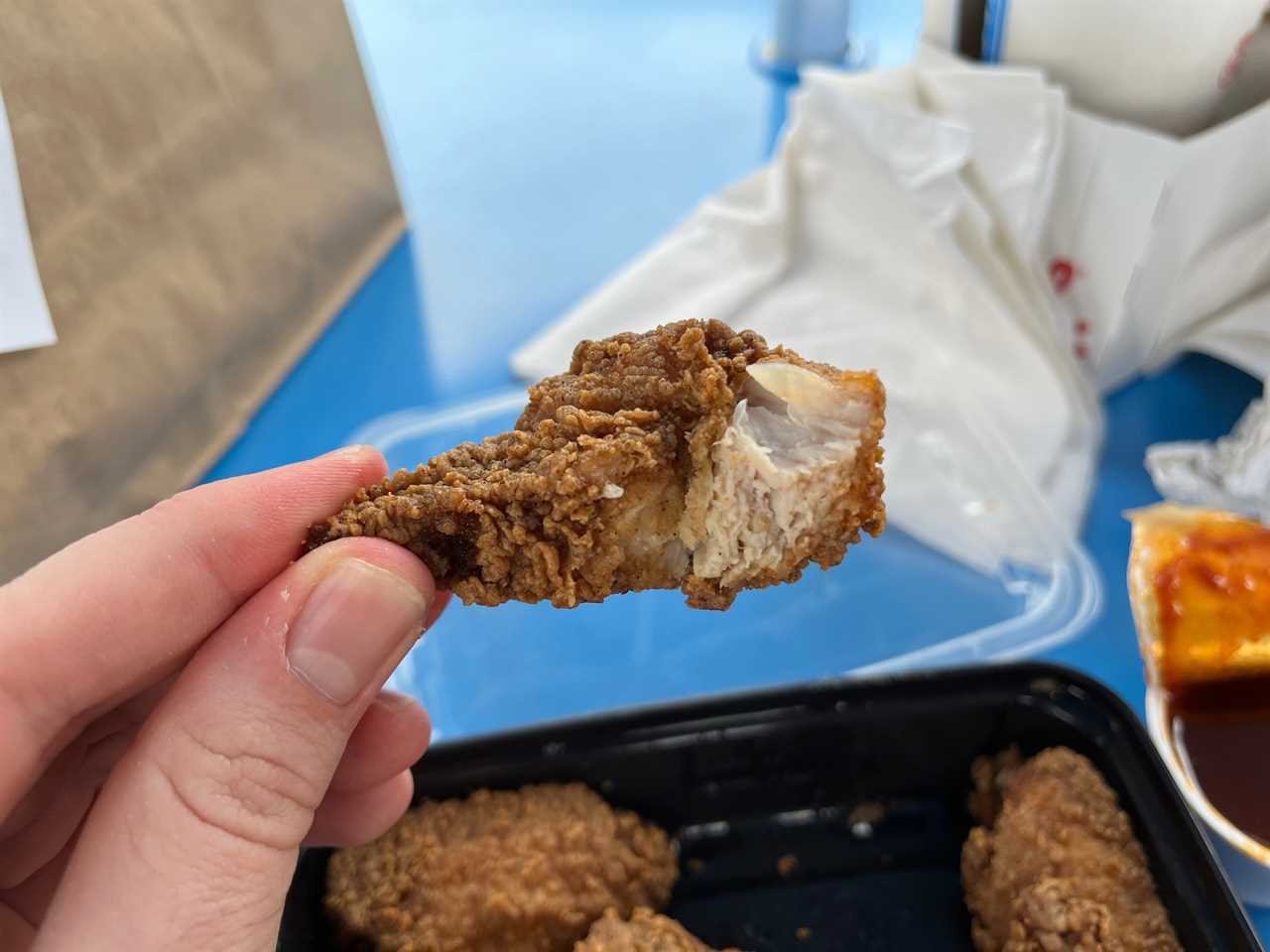 Insider reporter Alex Bitter holds a wing with a bite out of it at Little Blue Menu