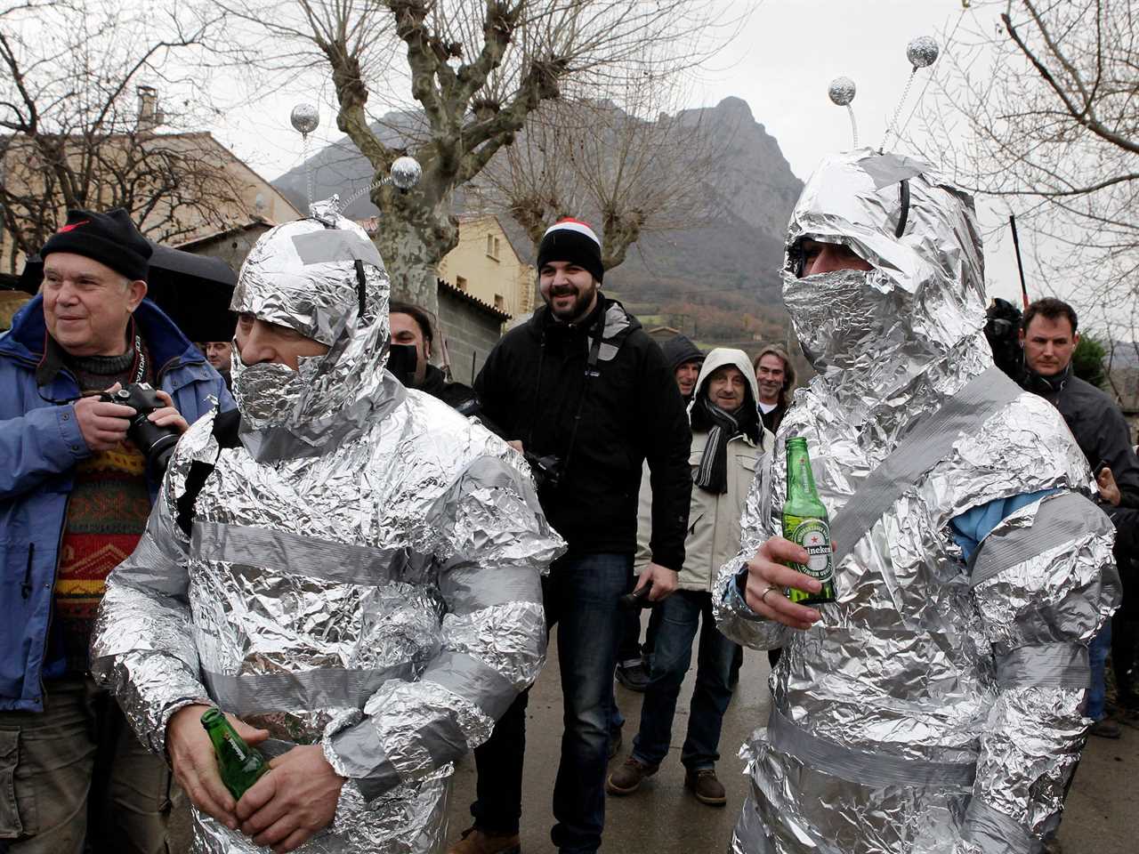 two people covered in tin foil except hands and eyes with alien antennaes stand in a crowd