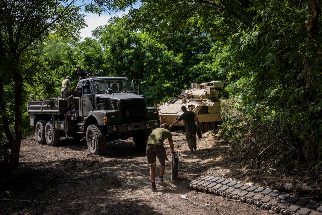 Soldiers and mechanics from Ukraine's 47th Mechanized Brigade go to change the wheels and tracks of a damaged US made Bradley Fighting Vehicle at a secret workshop in a wooded area in Zaporizhzhia Region, Ukraine