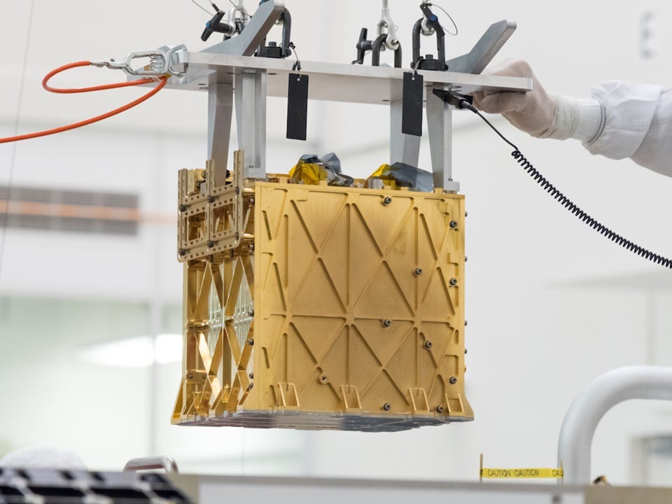 Technicians at NASA's Jet Propulsion Laboratory lower the Mars Oxygen In-Situ Resource Utilization Experiment (MOXIE) instrument into the belly of the Perseverance rover.