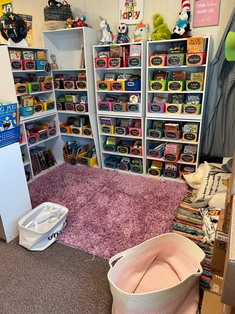 A photo of the "cozy corner" in Michelle Medintz's classroom, which includes baskets of books on shelves, a rug, and other items.