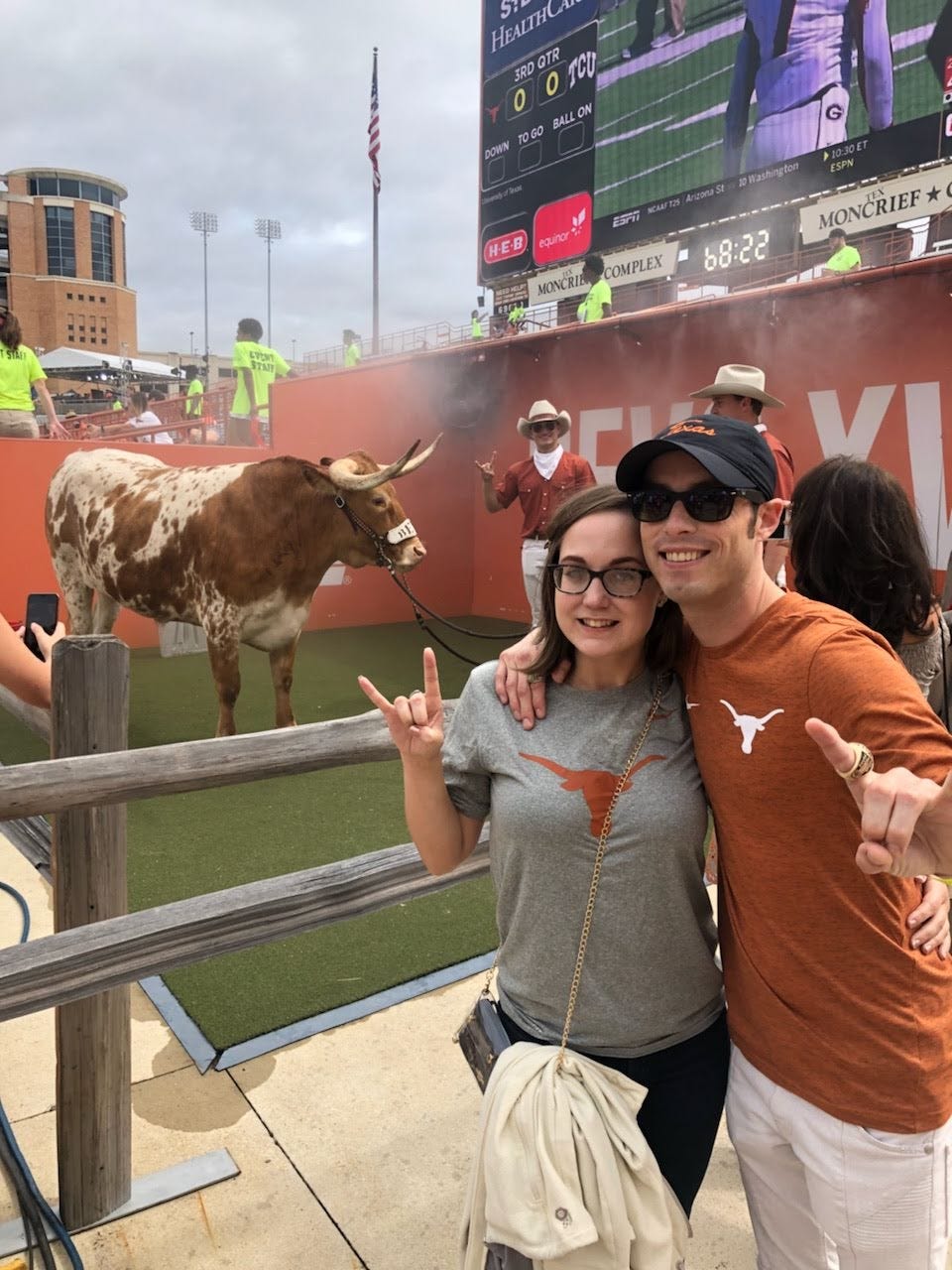 a couple stands in front of a bull at a rodeo