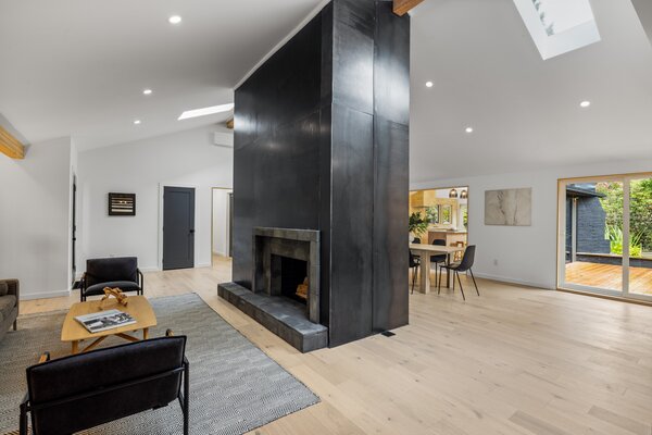 Inside, a soaring, steel-clad fireplace separates the spacious main living areas.