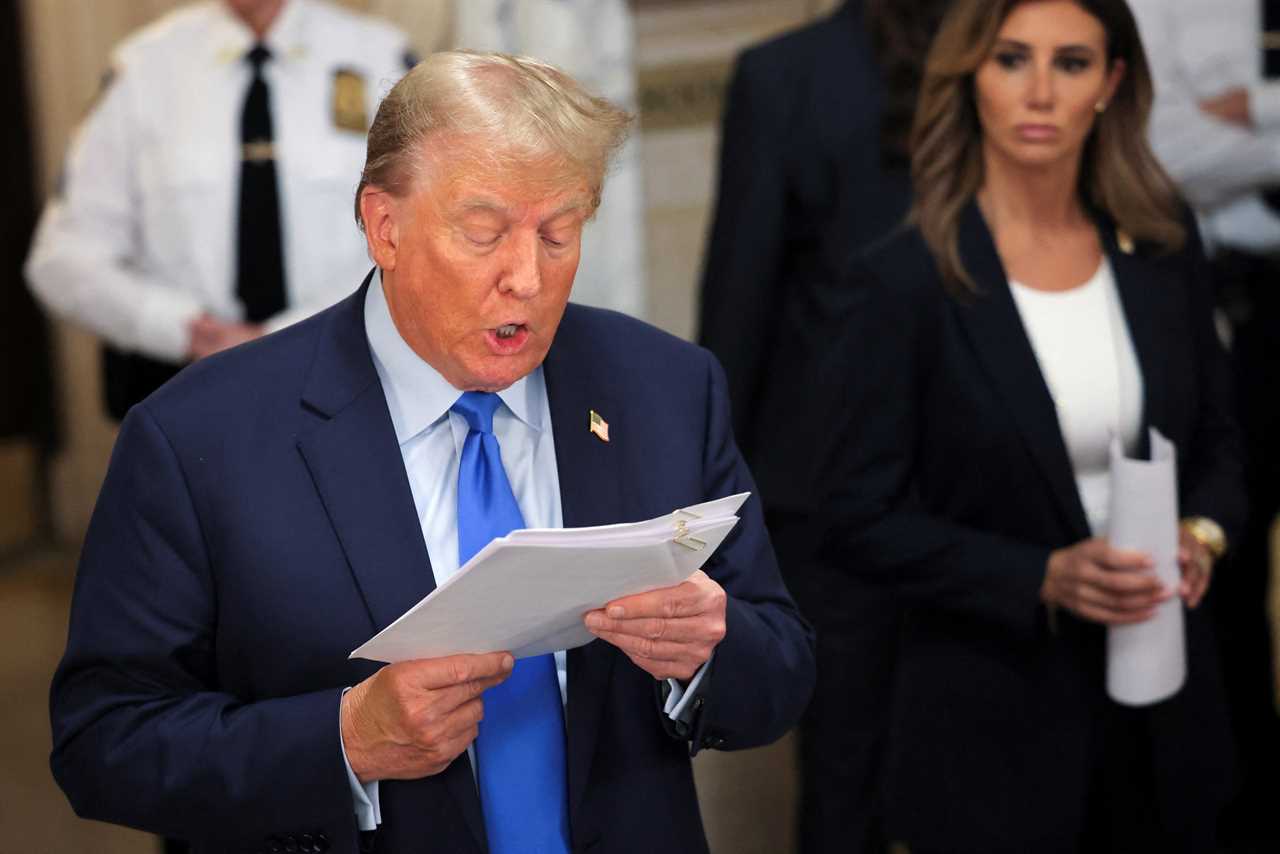 Donald Trump reading aloud from a piece of paper, with Alina Habba looking at him in the background.