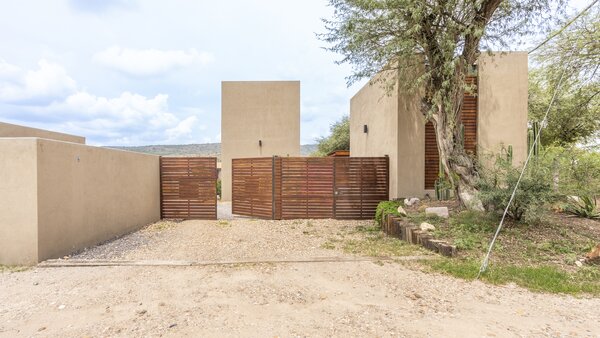 A handcrafted wooden gate extends a warm welcome to guests upon arrival, while also setting the stage for a peaceful, private retreat.