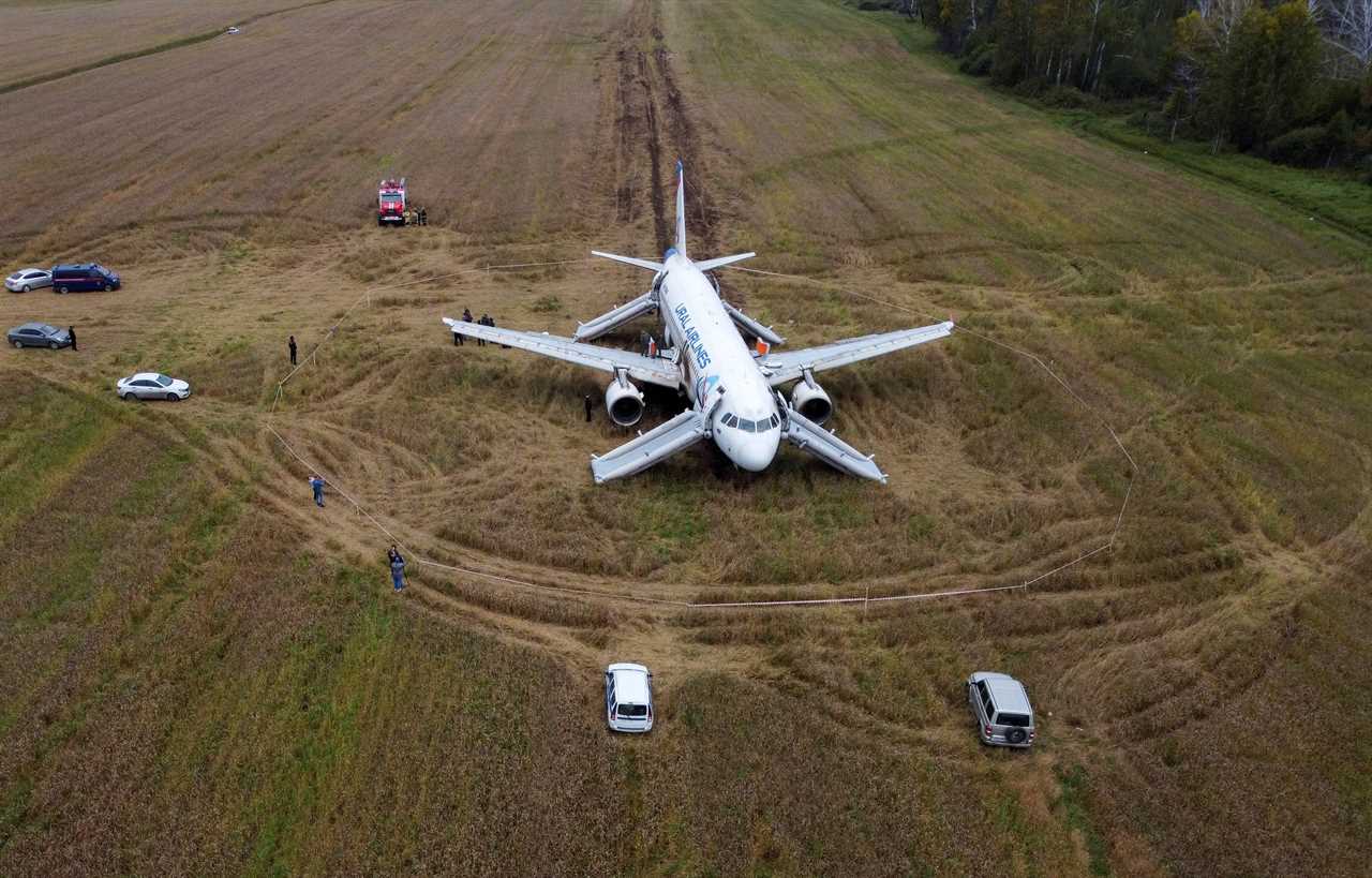 Ural A320 stranded in the field with cars and people around.