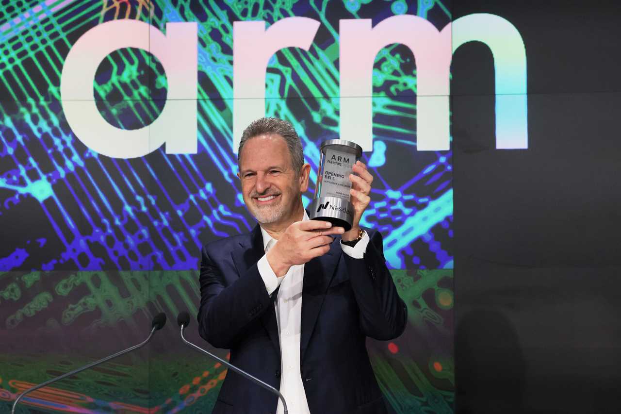 Rene Haas smiling whilst holding a NASDAQ memorabilia when the company IPO'd