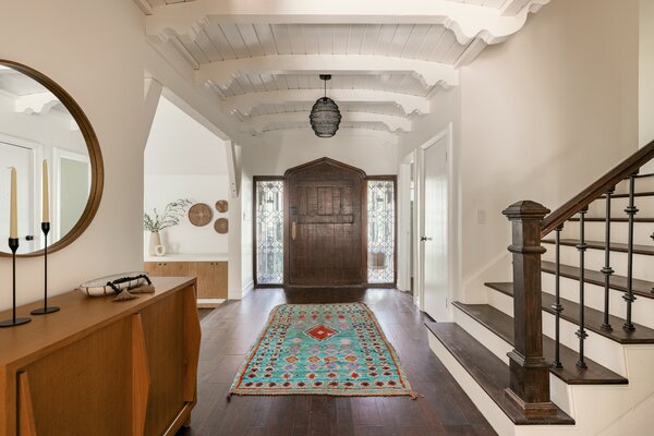 Beveled windows sandwich a wide wooden door, which opens to a large, beam-lined foyer.