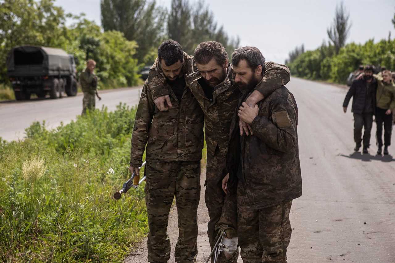 three Ukrainian prisoners of war holding each other in military uniform