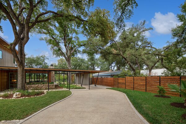 A curved driveway leads to an open carport which connects to the home's main entrance.