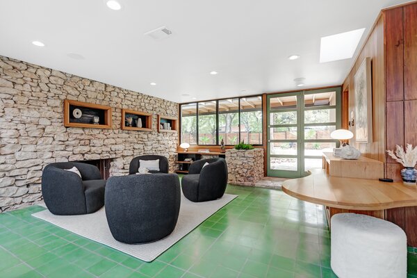 Upon entry, a bright-green tiled floor extends a warm welcome, popping against the surrounding stone and wood-paneled walls.