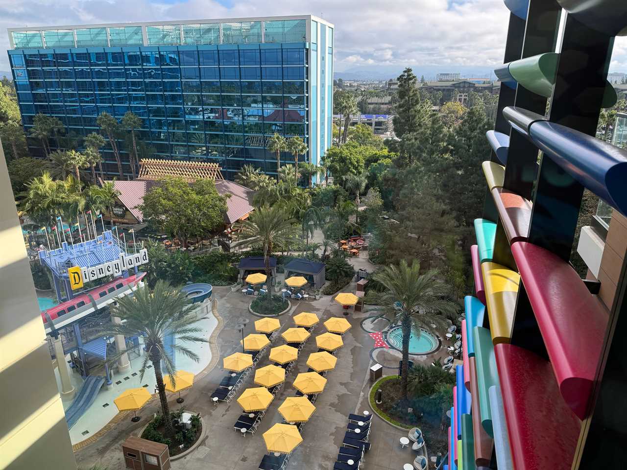 View from Disneyland hotel room of poolside yellow umbrellas and glass building on property