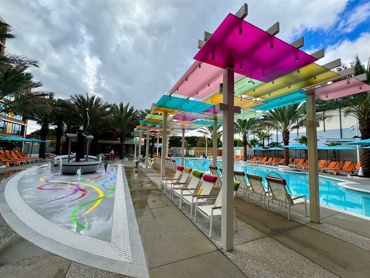 Pool at Disneyland villas with colorful awning and rows of chairs