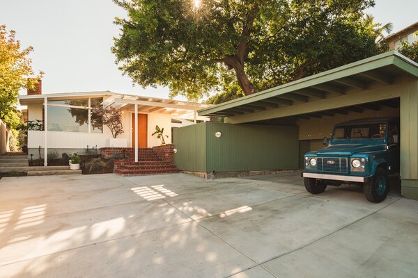 The home is surrounded by tall trees and a bordering fence, creating a private city oasis.