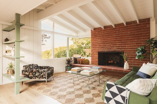 An original brick fireplace, along with its long hearth, anchors the sun-drenched living room.