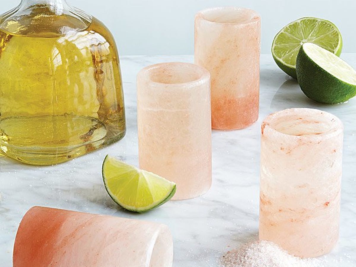 set of four shot glasses made from Himalayan pink salt set on a counter next to a bottle of tequila and limes