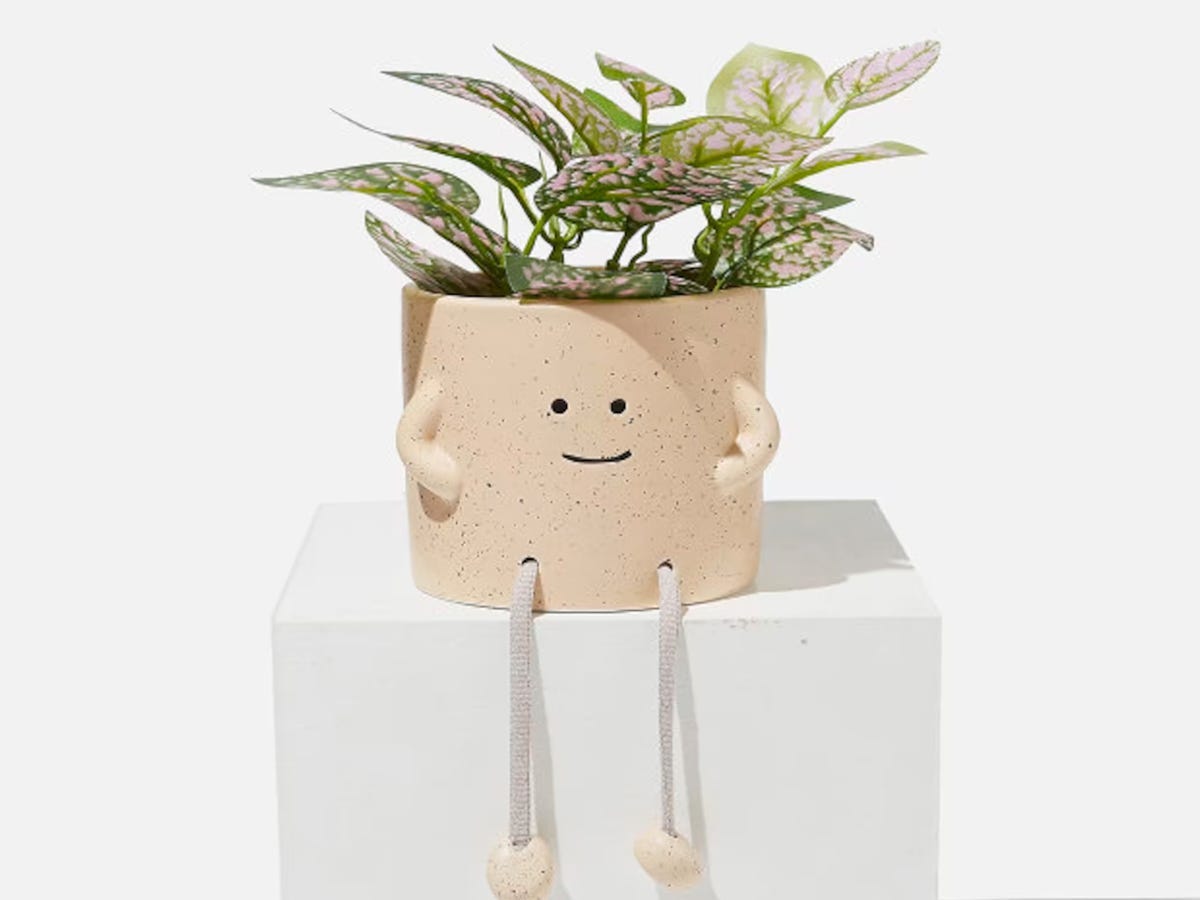 Sitting Planter with Dangling Legs holding a plant.