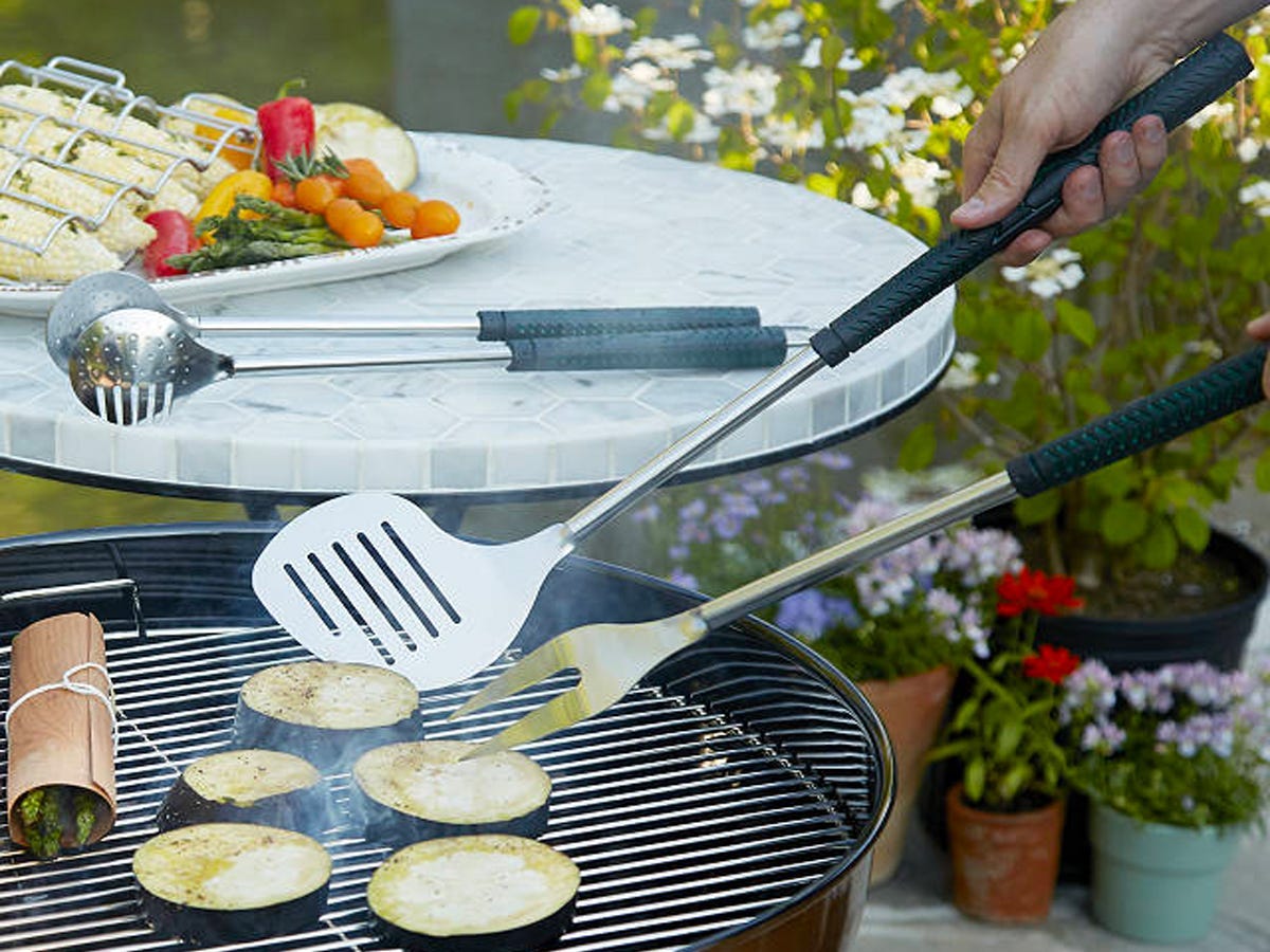 Person using the golf club shaped spatula in the Golfers BBQ Set to flip vegetables on a grill.