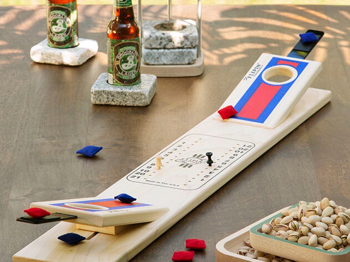 Tabletop Cornhole game with mini beanbags set on a table next to beers and a bowl of nuts.