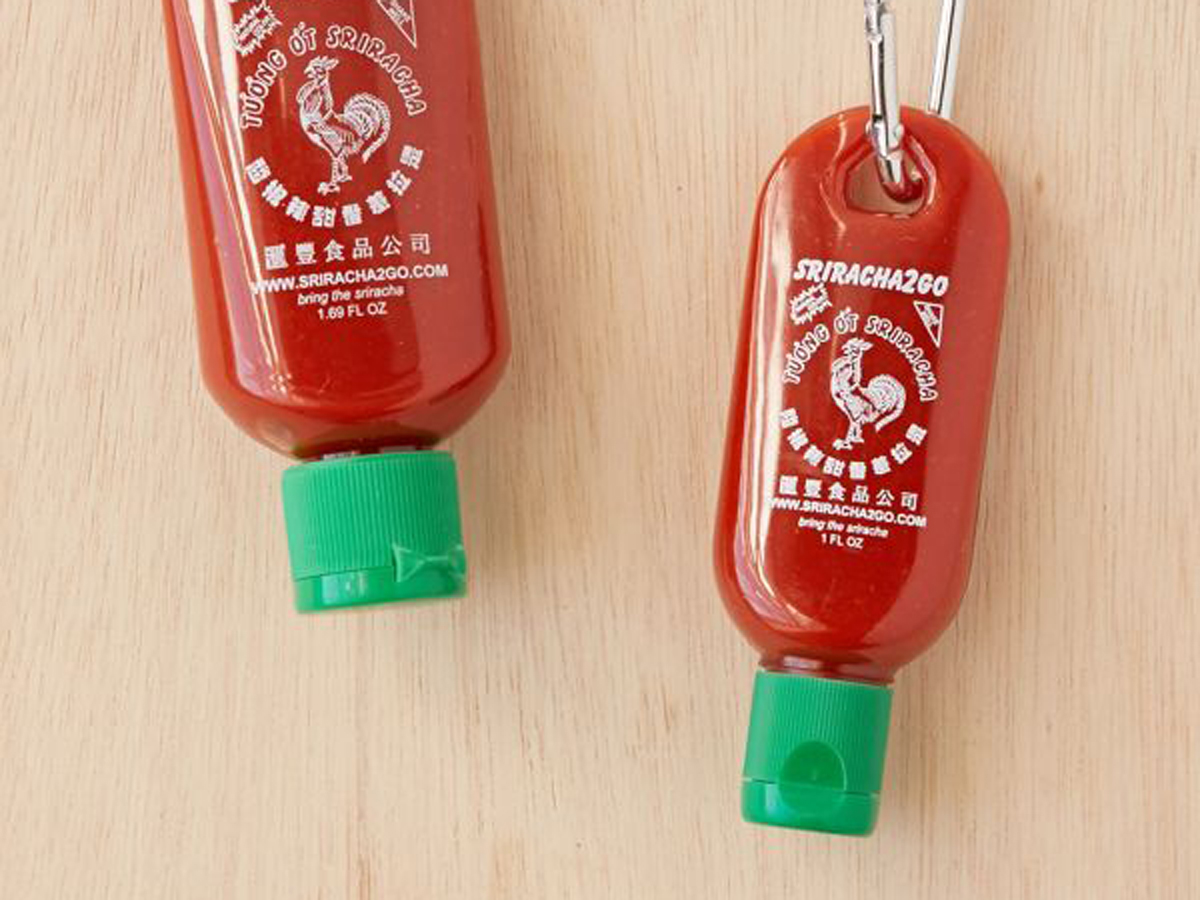 Two keychains shaped like sriracha sauce bottles