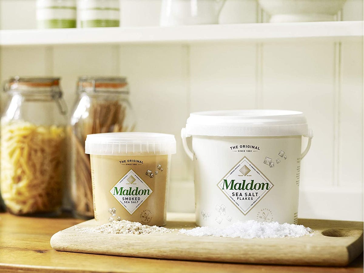 Two buckets of Maldon sea salt flakes set on a kitchen counter.