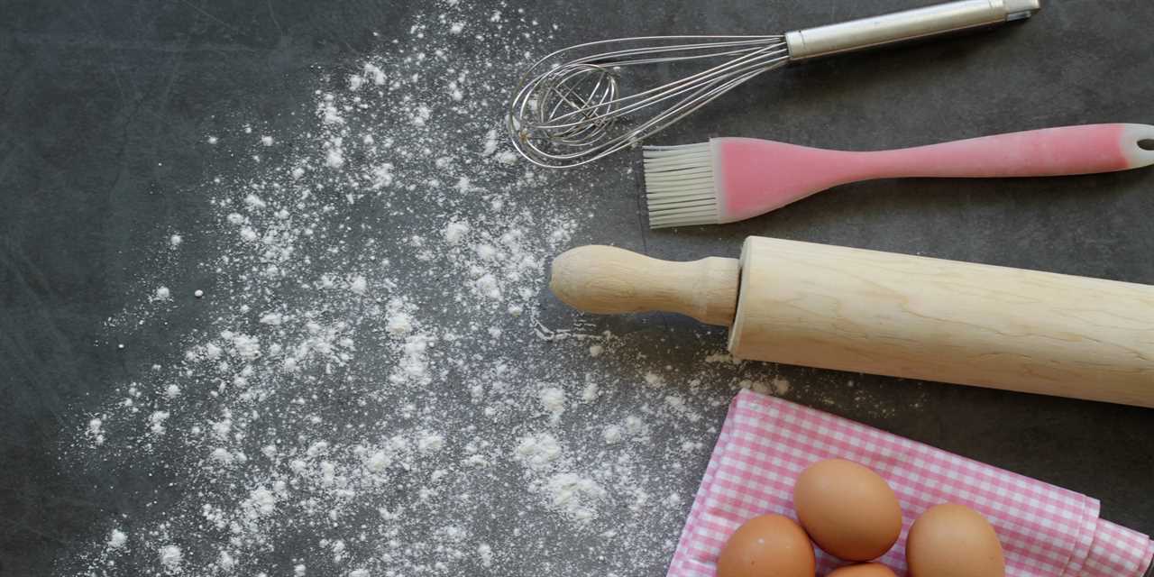 A rolling pin and other baking utensils next to sprinkles of flour and five eggs on a counter top.