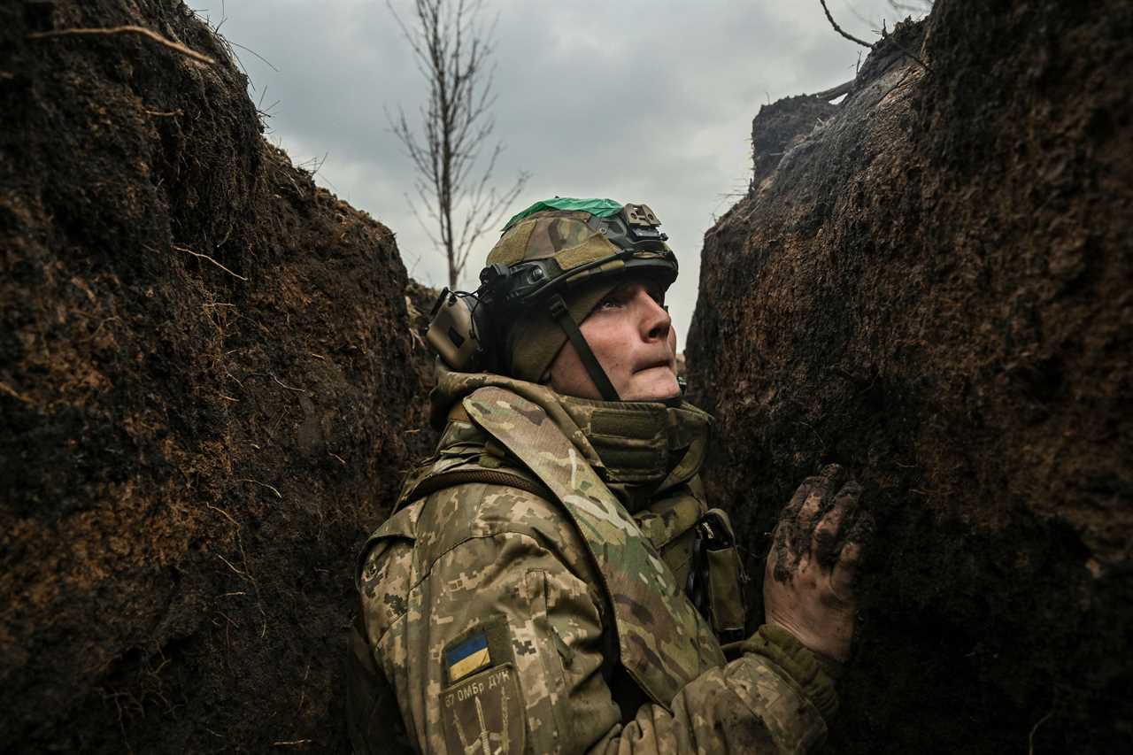 A Ukrainian serviceman takes cover in a trench during shelling next to a 105mm howitzer near the city of Bakhmut, on March 8, 2023, amid the Russian invasion of Ukraine.